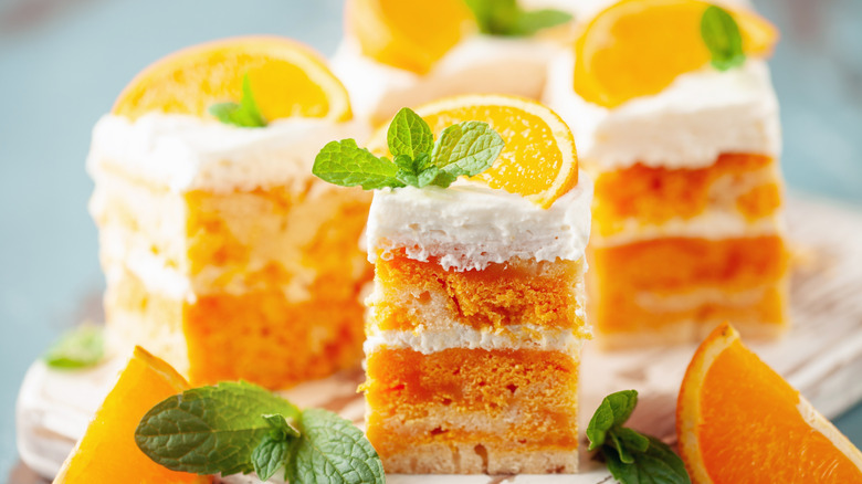 Slices of orange cake with white frosting and fresh orange segments on top