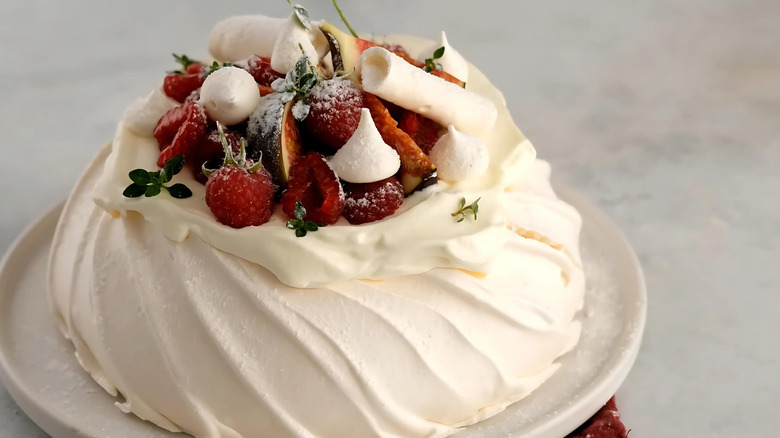 A classic pavlova decorated with raspberries and white chocolate