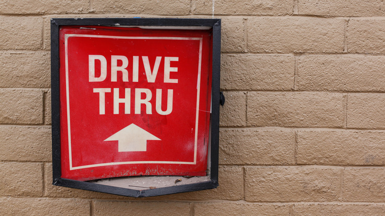 a drive-thru sign mounted on a beige brick wall