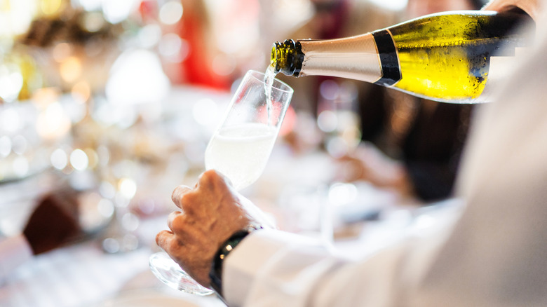 A person pouring Champagne into a glass.