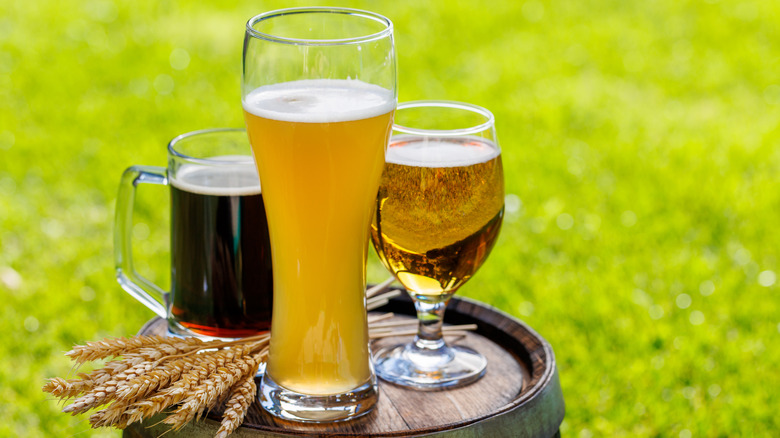 Selection of beers, in glasses, on a wooden cask.