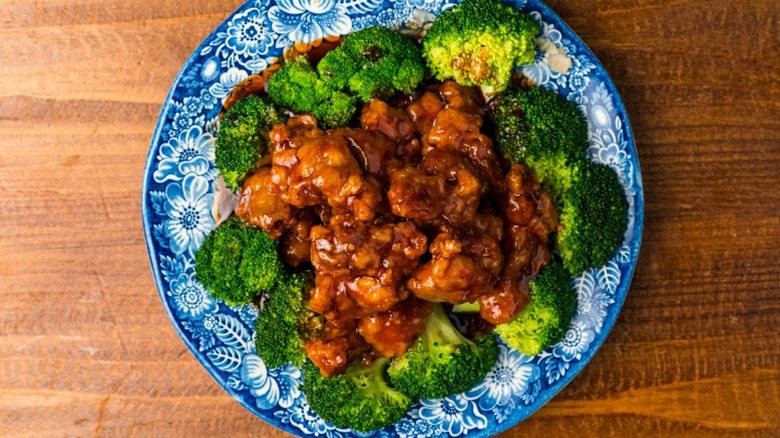 General Tso's chicken served with broccoli on a blue china plate.