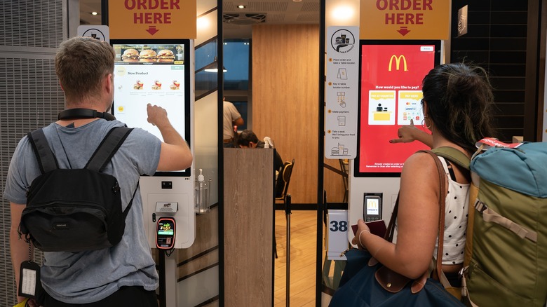 People placing orders at Mcdonald's kiosks