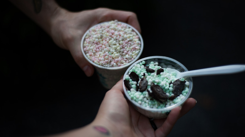 close up of two hands holding cups of Dippin' Dots