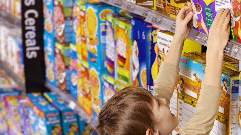 Child reaching for cereal in supermarket