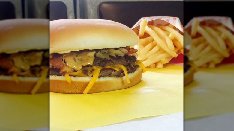 Burger with melted cheese next to fries from Whataburger