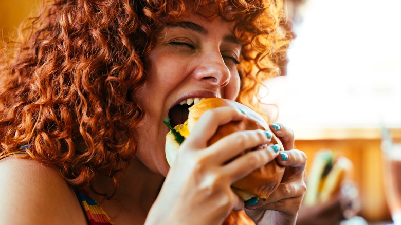 Woman with curly hair eating burger