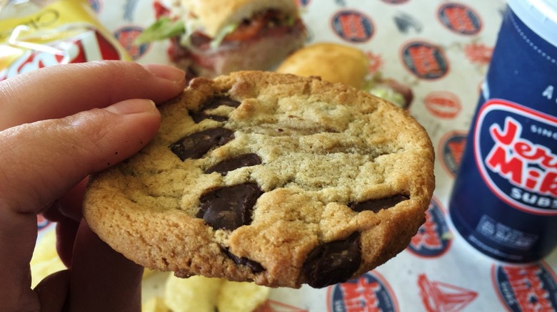 Hand holding cookie next to Jersey Mike's cup