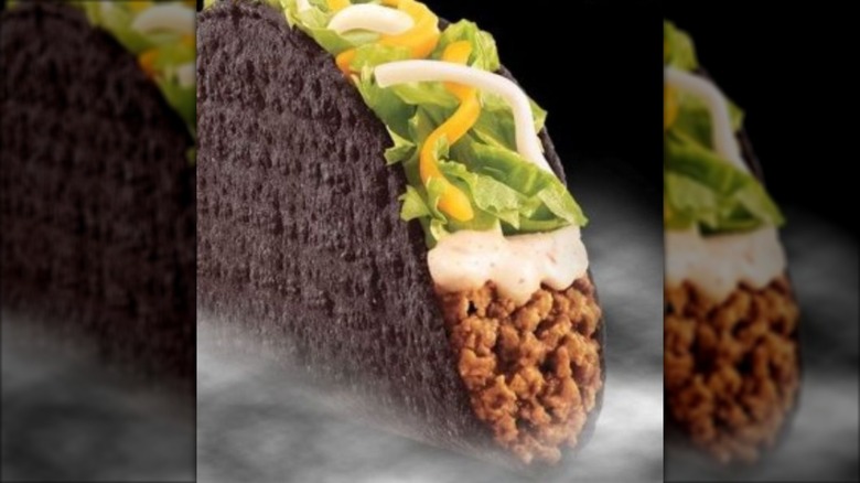 Black taco with beef, sour cream, lettuce, and cheese