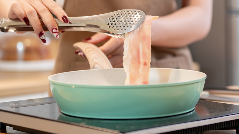 flipping bacon in pan with tongs