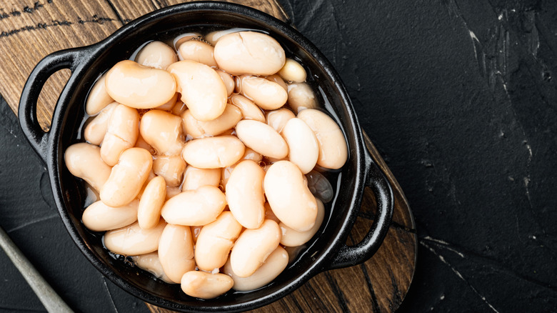 Overhead shot of white beans in a black crock, sitting on a table