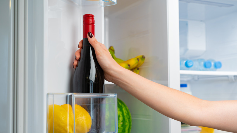 A bottle of wine being stored in a fridge.