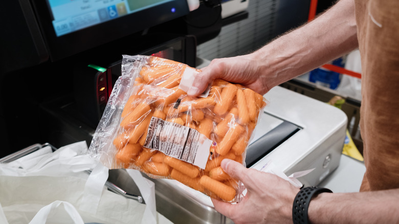 man buying baby carrots at the grocery store