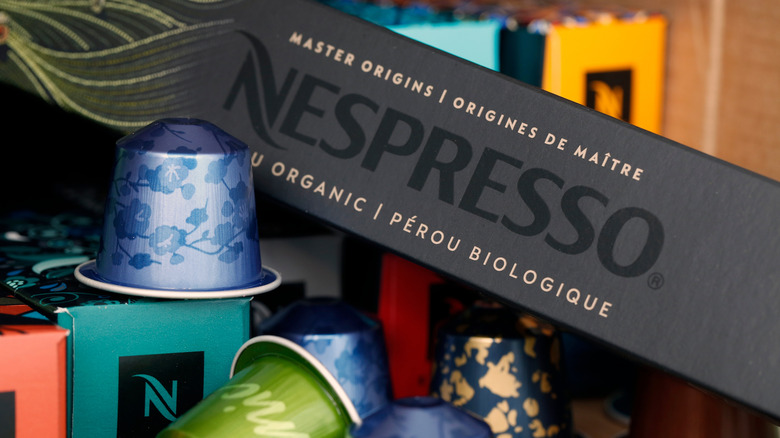 sleeves of Nespresso pods surrounded by different flavors of vibrant Nespresso coffee cups