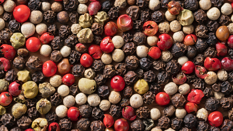 A mix of black, white, red, and green peppercorns