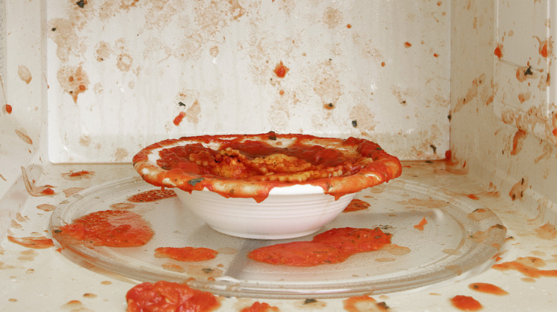 A bowl with pasta sauce has exploded inside a white microwave