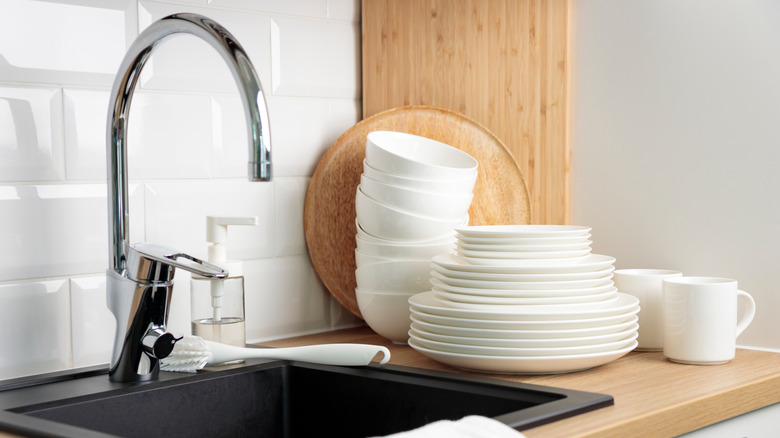 Clean white plates and bowls next to a kitchen sink