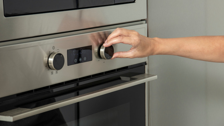 A hand adjusting the cooking time on an oven