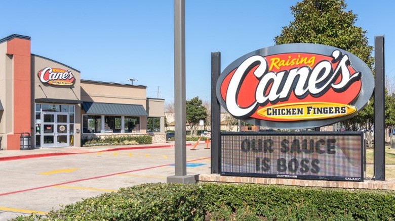 A sign outside a Raising Cane's location that reads "Our Sauce Is Boss".