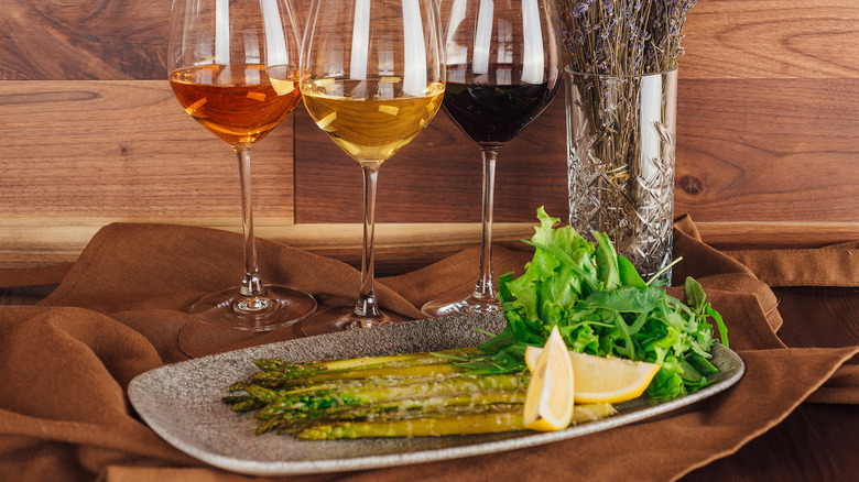 Plate of asparagus with three glasses of wine