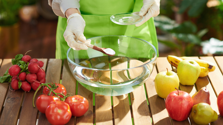 woman removing pesticides from produce with baking soda and water solution