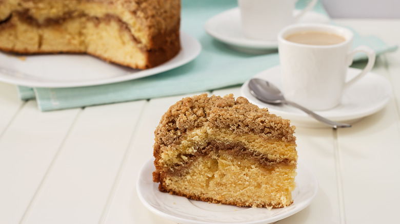 A slice of coffee cake with cinnamon and streusel served with coffee.