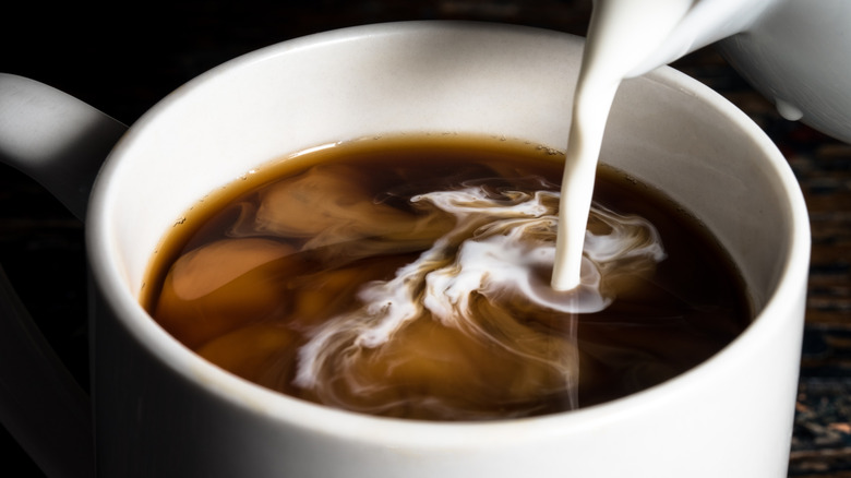 creamer being poured into a cup of coffee