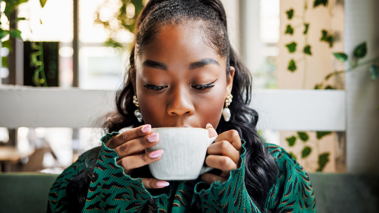 woman drinking coffee from a coffee cup in a cafe