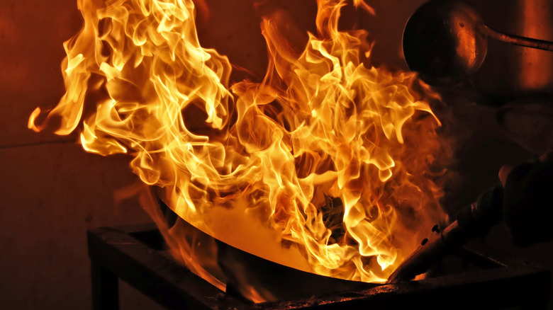 A cooking fire erupts in a wok