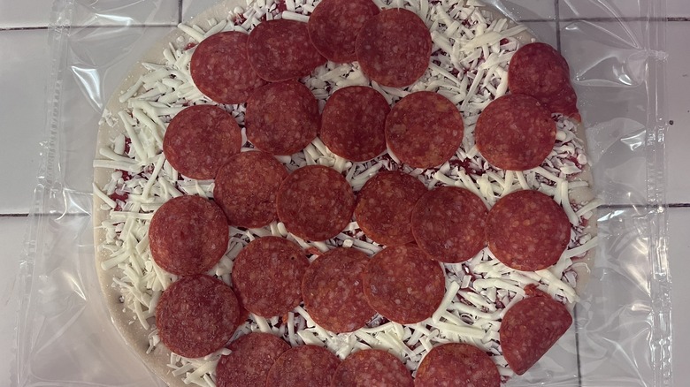 Close up a frozen pizza thawing on a tiled countertop