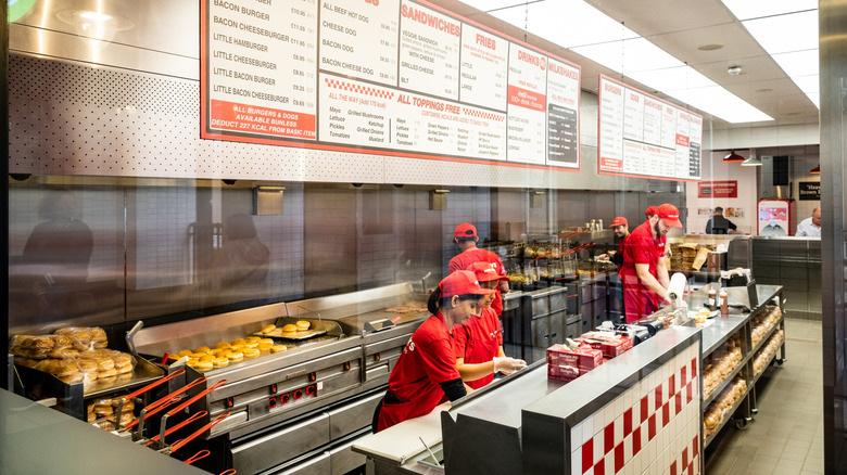 Staff in red uniforms working in a Five Guys restaurant