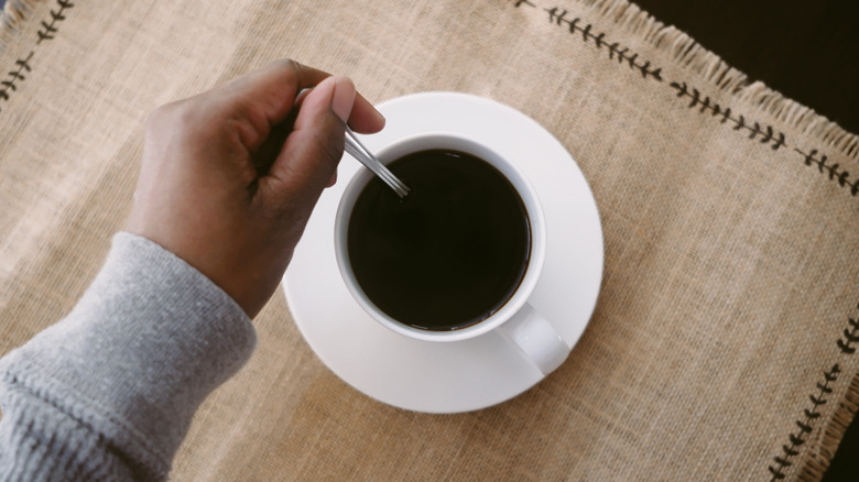 hand stirring a cup of coffee