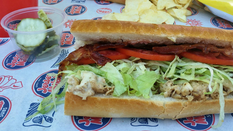 An open Jersey Mike's sub with chicken salad, bacon, lettuce, and sliced tomato