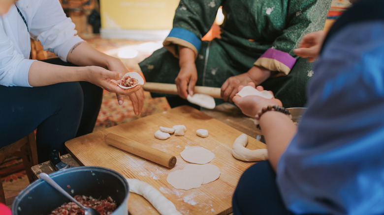 Preparing buuz dumplings around wood board