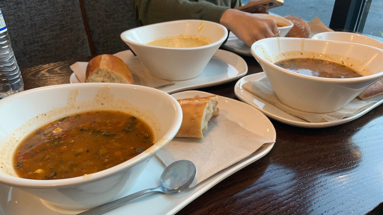 Three large bowls of Panera soup options are shown on a table