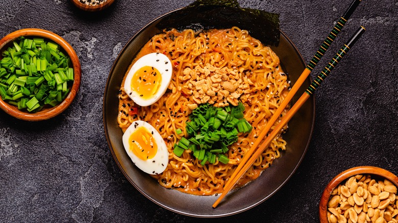 Bowl of Korean ramen noodles with chopped peanuts, boiled egg, and scallions