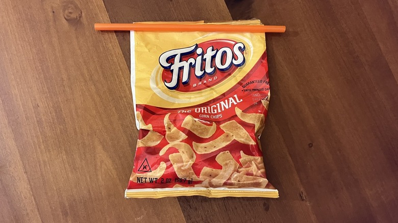 An open bag of Fritos chips and an orange straw