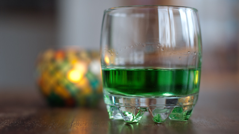 Glass of green absinthe on a wooden table