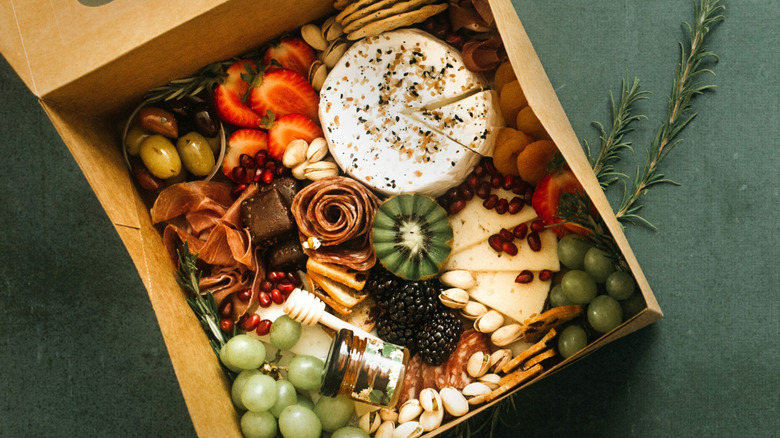 Charcuterie meats, cheese, and fruit in brown cardboard box