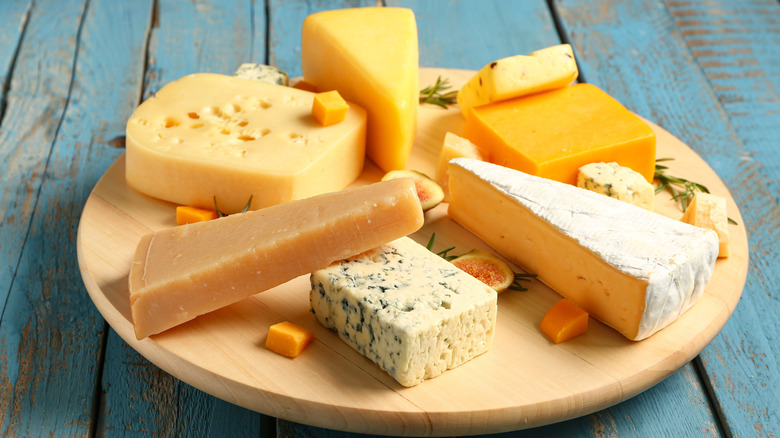 Board with a variety of cheese on blue wooden background.