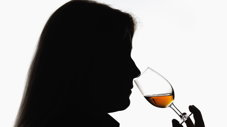 Woman sniffs whiskey glass 