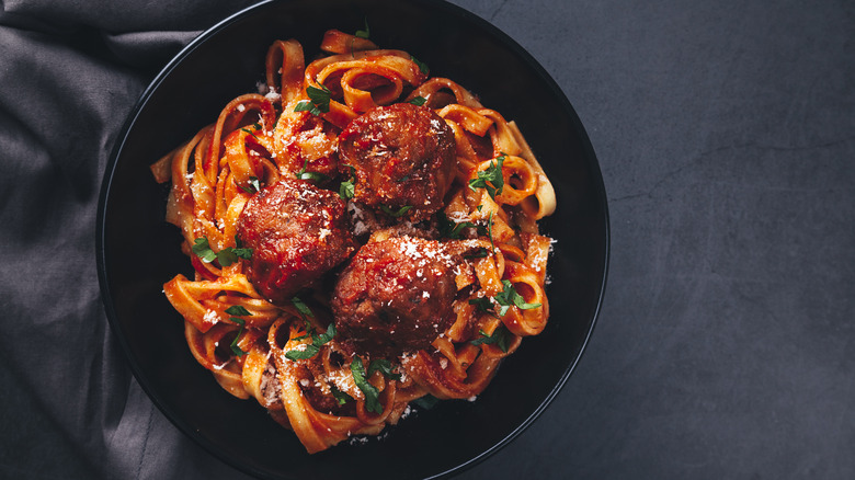 Pasta and meatballs in a black bowl