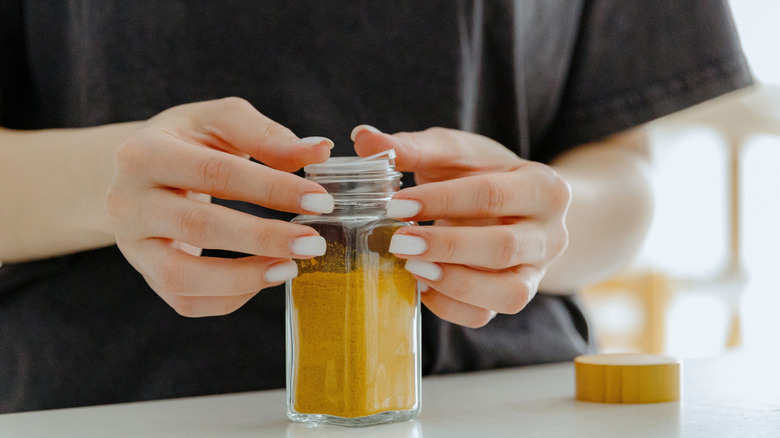 Person closing lid on spice jar