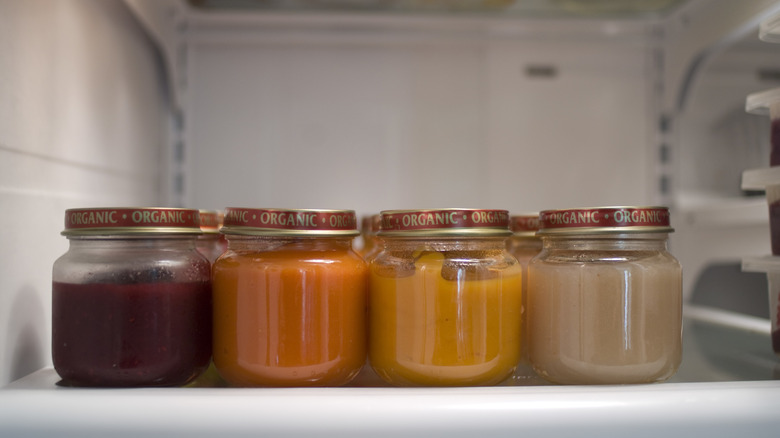 Glass jars of sauce lined up on fridge shelf