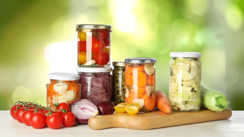 Jars of pickled vegetables on a wooden board