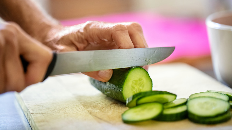 Close-up of person slicing cucumber