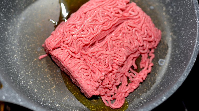 Ground beef cooking in oil in a skillet