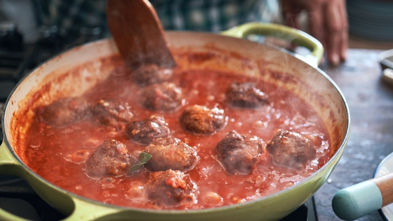 Cooking meatballs in red sauce in a pot on the stove