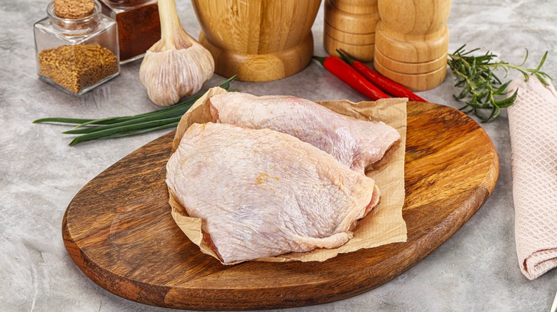 raw skin-on chicken thighs on a cutting board