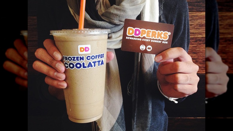 Person with Dunkin' coffee Coolatta and perks card